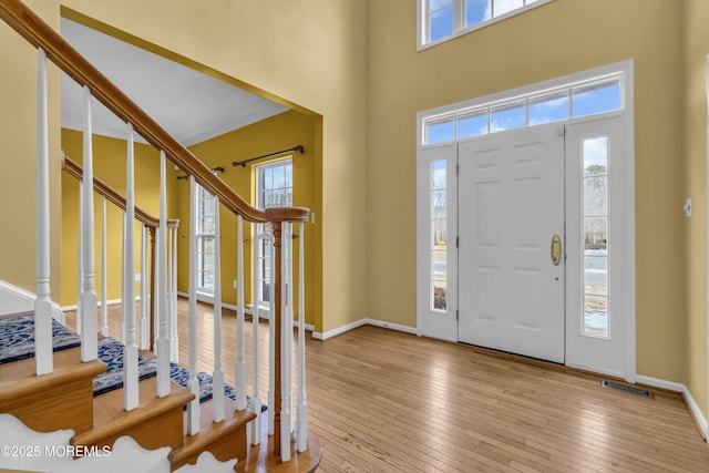 entryway with a towering ceiling and light hardwood / wood-style flooring