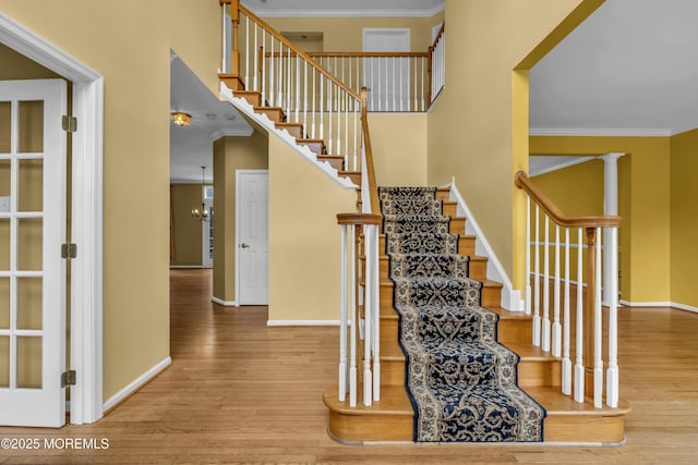 stairway with an inviting chandelier, hardwood / wood-style flooring, and ornamental molding