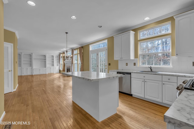 kitchen with sink, white cabinetry, ornamental molding, decorative light fixtures, and stainless steel dishwasher