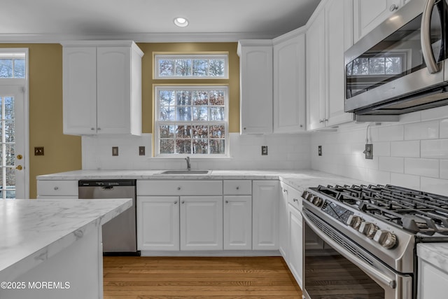 kitchen with white cabinetry, stainless steel appliances, sink, and backsplash