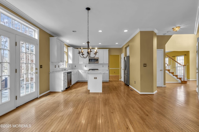 kitchen with a kitchen island, white cabinetry, decorative backsplash, hanging light fixtures, and stainless steel appliances