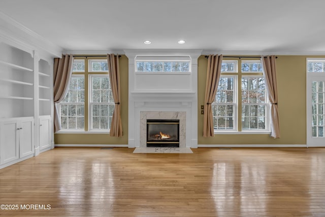 unfurnished living room with plenty of natural light, a high end fireplace, and light wood-type flooring