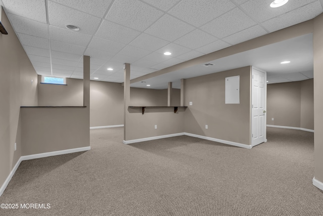 basement featuring carpet flooring, a drop ceiling, and electric panel