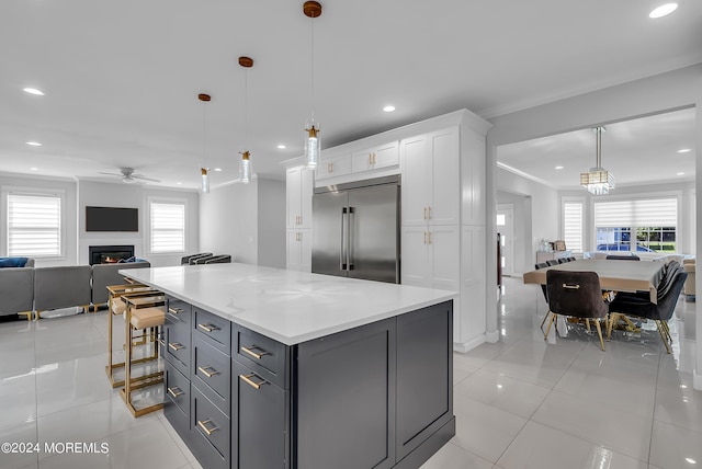 kitchen featuring pendant lighting, light tile patterned floors, white cabinetry, ornamental molding, and built in fridge