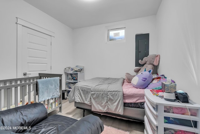 bedroom with electric panel and light wood-type flooring