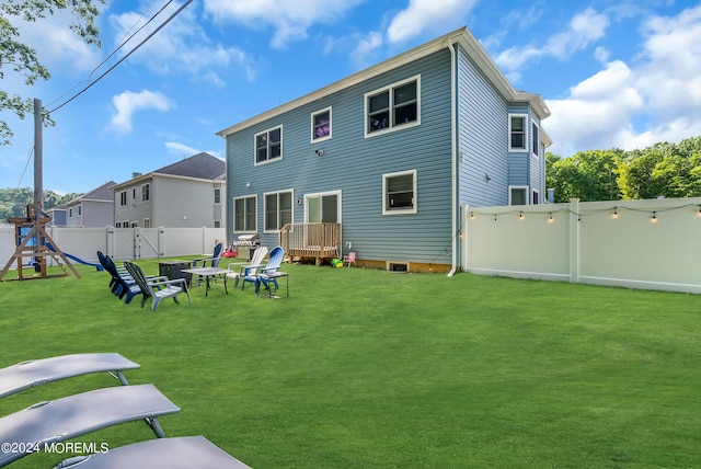 rear view of house with a playground and a yard