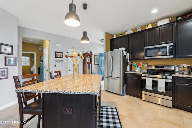 kitchen featuring appliances with stainless steel finishes, a kitchen island, a kitchen bar, and hanging light fixtures