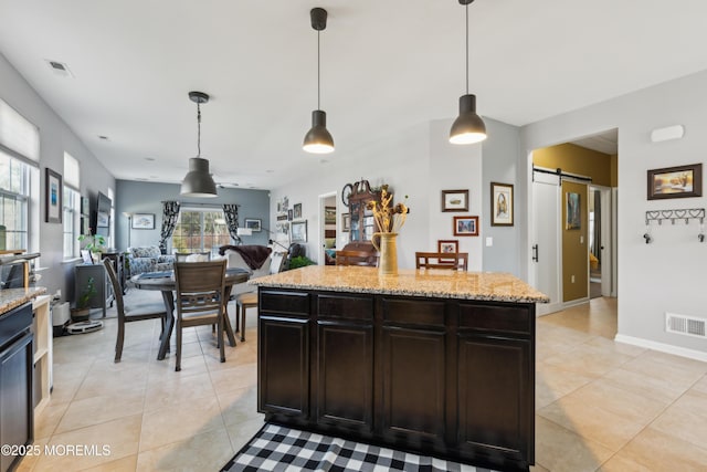 kitchen featuring light tile patterned floors, hanging light fixtures, dark brown cabinets, a kitchen island, and a barn door