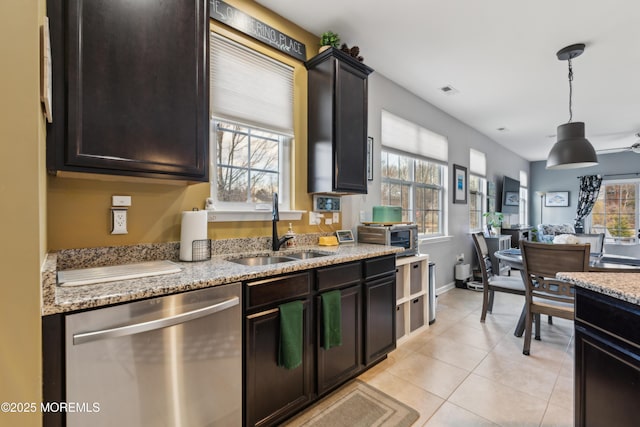 kitchen featuring light tile patterned flooring, sink, hanging light fixtures, stainless steel dishwasher, and light stone counters