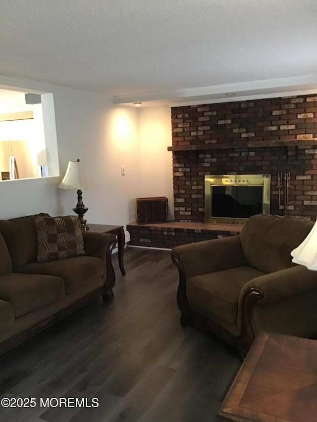 living room featuring dark hardwood / wood-style flooring, a brick fireplace, and a textured ceiling