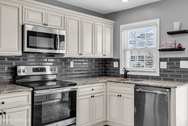 kitchen with sink, tasteful backsplash, dark stone countertops, stainless steel appliances, and cream cabinets