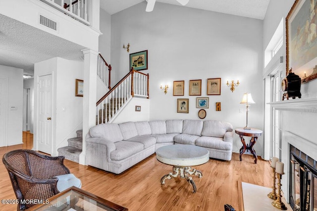 living room featuring wood-type flooring, high vaulted ceiling, and a textured ceiling