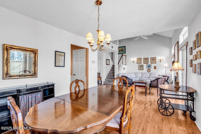 dining area with lofted ceiling, light hardwood / wood-style floors, a textured ceiling, and a notable chandelier