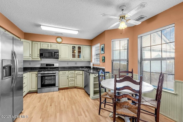 kitchen featuring green cabinets, stainless steel appliances, light hardwood / wood-style floors, and a textured ceiling