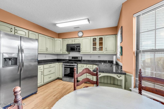 kitchen with sink, green cabinets, appliances with stainless steel finishes, a textured ceiling, and light wood-type flooring