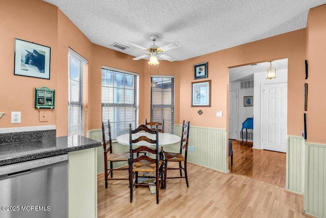 dining room with ceiling fan, a textured ceiling, and light wood-type flooring