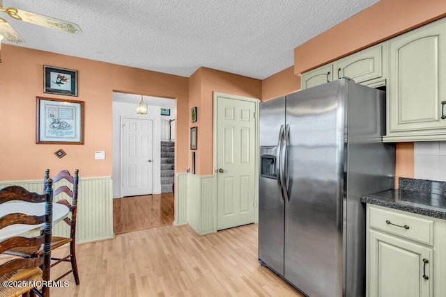 kitchen featuring green cabinets, a textured ceiling, light hardwood / wood-style floors, and stainless steel fridge with ice dispenser