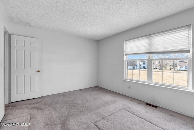 carpeted empty room with a textured ceiling