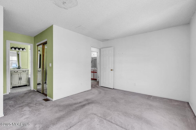 empty room with light colored carpet and a textured ceiling