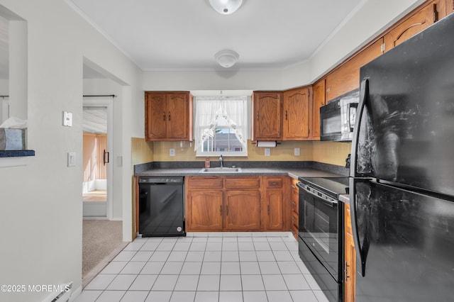 kitchen featuring a sink, brown cabinets, black appliances, dark countertops, and crown molding