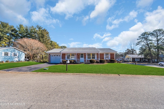 view of front of property featuring brick siding, covered porch, an attached garage, a front yard, and driveway