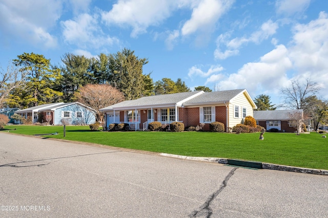 ranch-style house featuring covered porch, brick siding, and a front lawn