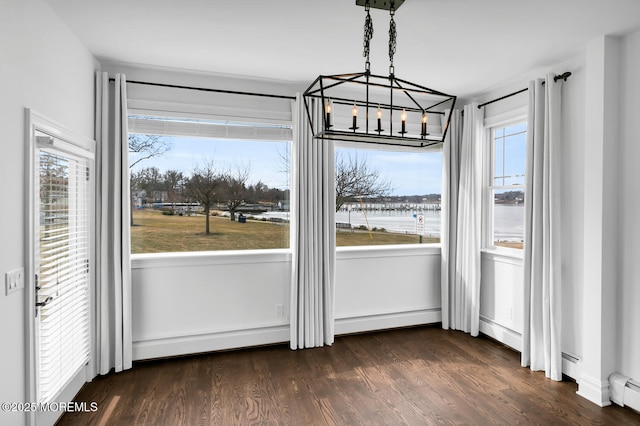 unfurnished dining area with a water view, a healthy amount of sunlight, dark hardwood / wood-style flooring, and baseboard heating