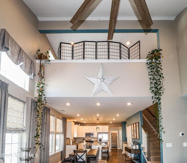 living room featuring wood-type flooring, beam ceiling, and a high ceiling