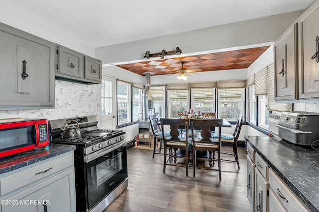 kitchen with dark wood-type flooring, gray cabinets, ceiling fan, stainless steel range with gas stovetop, and tasteful backsplash