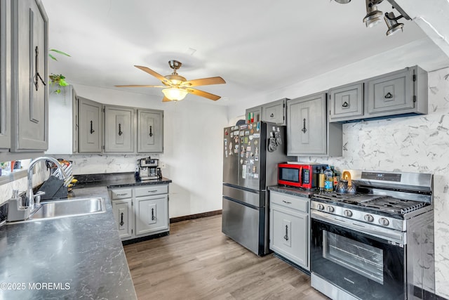 kitchen with gray cabinets, hardwood / wood-style floors, sink, decorative backsplash, and stainless steel appliances