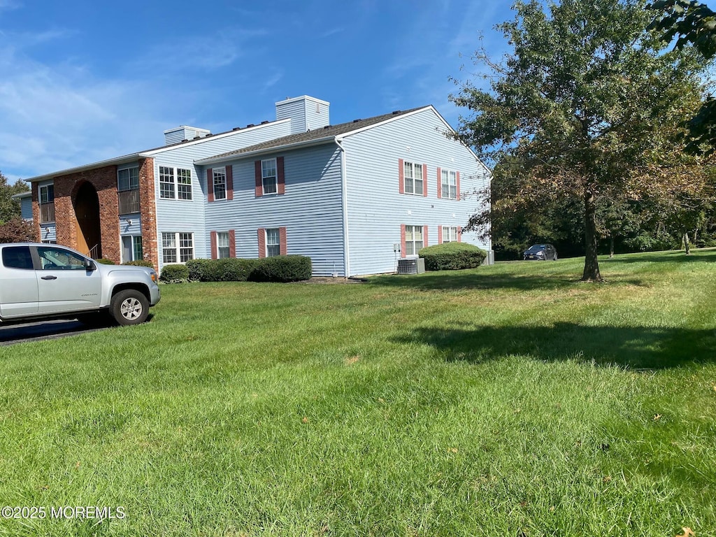 view of property exterior with central AC and a yard