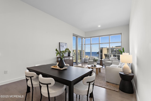 dining space with a water view, recessed lighting, dark wood finished floors, and baseboards