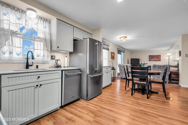 kitchen with stainless steel appliances, sink, light hardwood / wood-style flooring, and a wealth of natural light