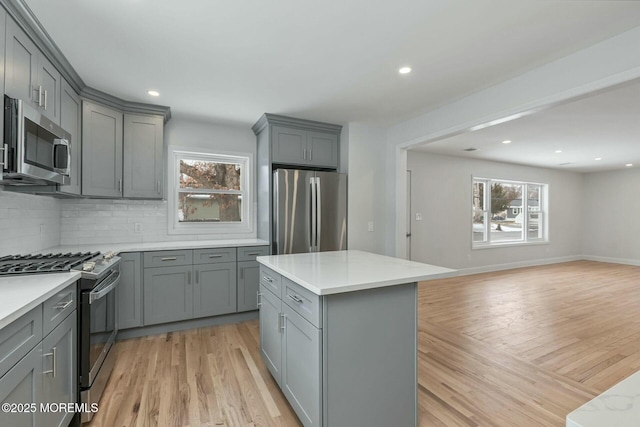 kitchen with decorative backsplash, appliances with stainless steel finishes, light hardwood / wood-style flooring, and gray cabinetry