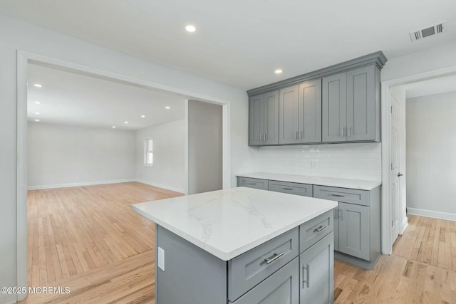 kitchen featuring a kitchen island, gray cabinetry, light hardwood / wood-style floors, and decorative backsplash