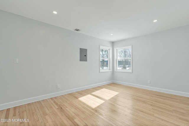 empty room featuring electric panel and light hardwood / wood-style floors