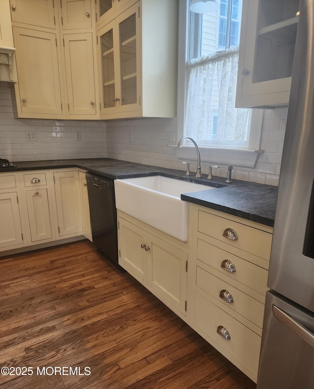 kitchen featuring a sink, dark countertops, black appliances, and dark wood finished floors