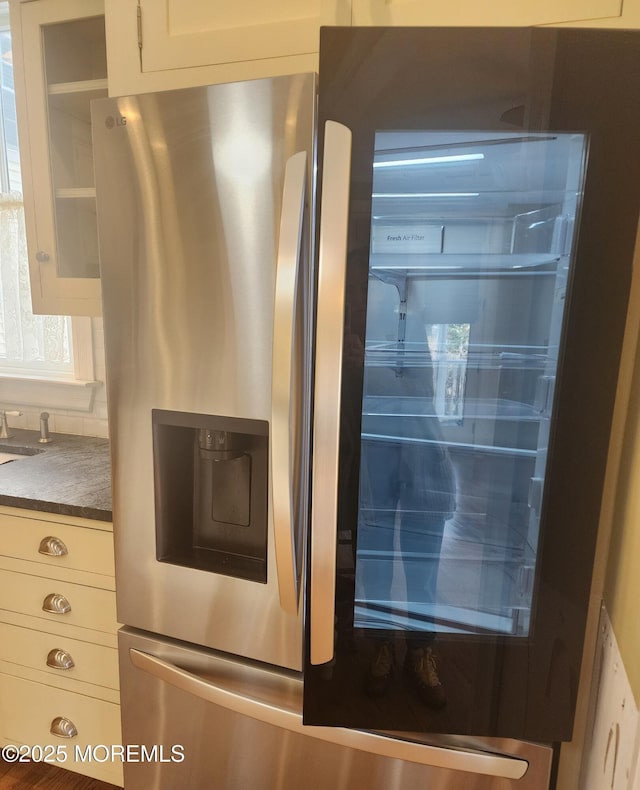 room details featuring dark countertops, white cabinetry, and stainless steel fridge with ice dispenser