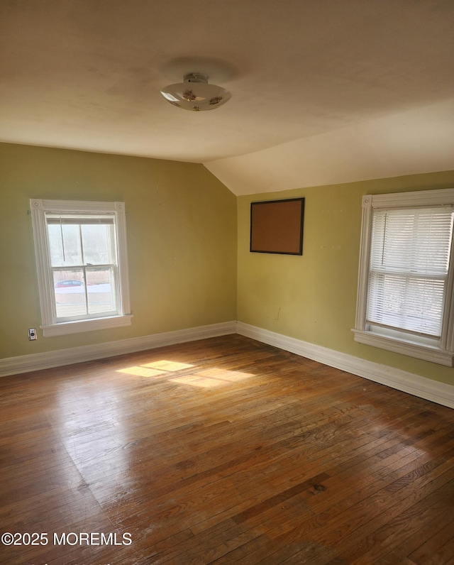 empty room with lofted ceiling, baseboards, and wood-type flooring