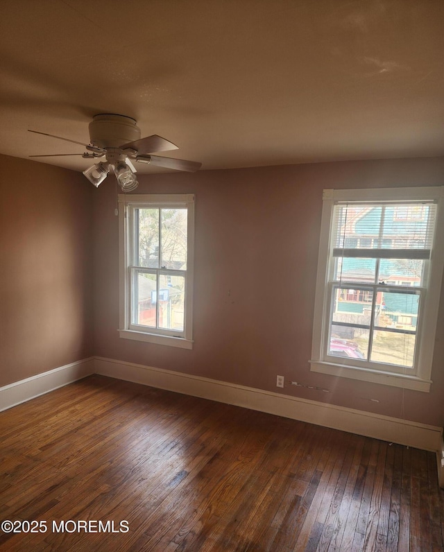 spare room featuring ceiling fan, baseboards, and dark wood finished floors