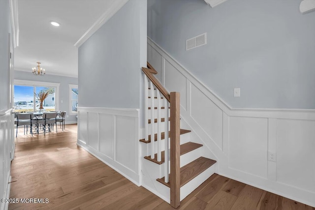 302 Reef Ct, Forked River, NJ 08731 - stairway with a decorative wall, a chandelier, wood finished floors, a wainscoted wall, and crown molding