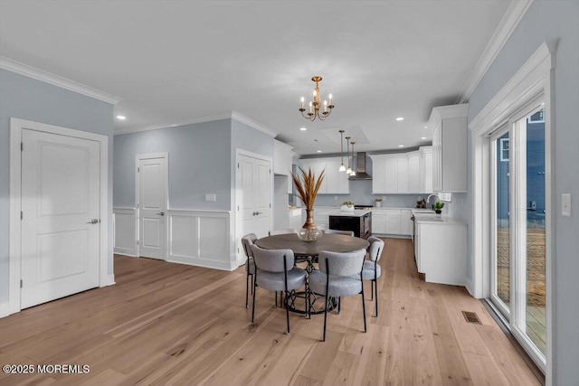 302 Reef Ct, Forked River, NJ 08731 - dining area with a chandelier, light wood-style flooring, crown molding, healthy amount of natural light, and wainscoting