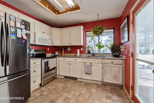 kitchen with sink, light stone countertops, white cabinets, and appliances with stainless steel finishes