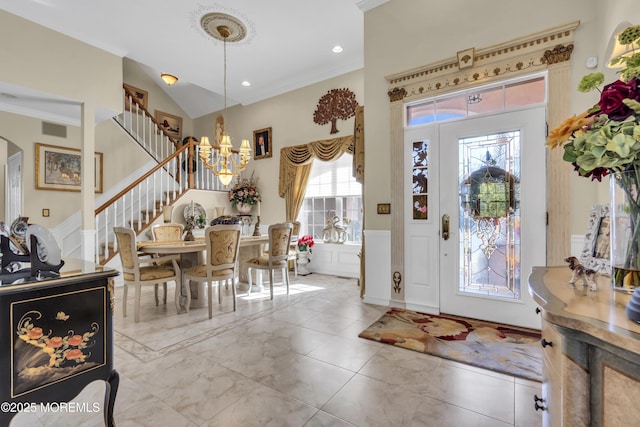 entrance foyer featuring vaulted ceiling, ornamental molding, and a notable chandelier