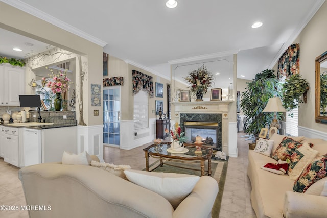 living room featuring sink, crown molding, and a high end fireplace