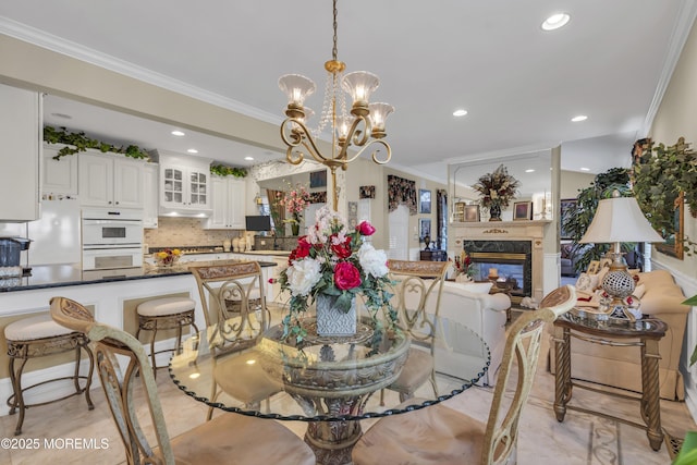 dining area with ornamental molding, a high end fireplace, and a notable chandelier