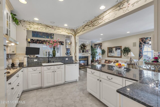 kitchen featuring white cabinetry, sink, dark stone countertops, white dishwasher, and kitchen peninsula