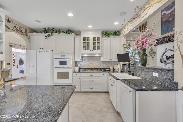 kitchen with sink, dark stone countertops, white cabinets, white appliances, and backsplash