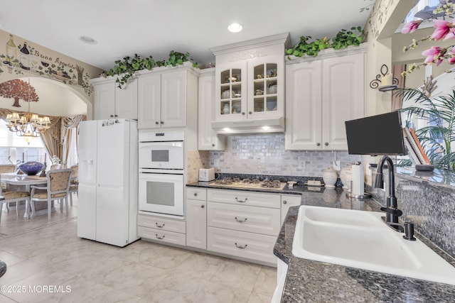 kitchen featuring sink, white appliances, white cabinetry, decorative backsplash, and a chandelier