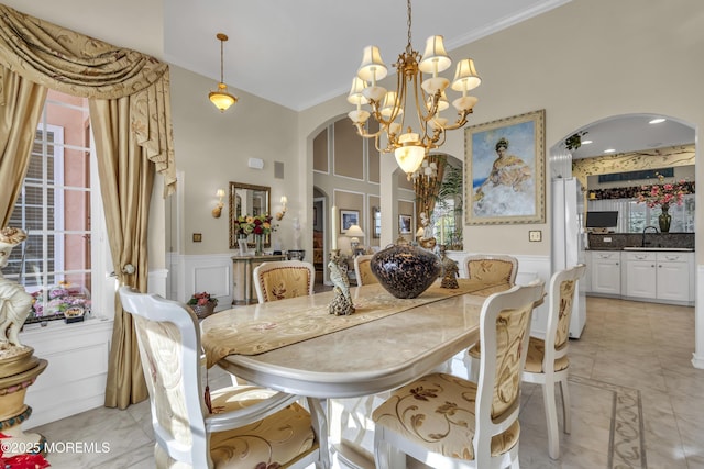 tiled dining room featuring crown molding, sink, an inviting chandelier, and a high ceiling